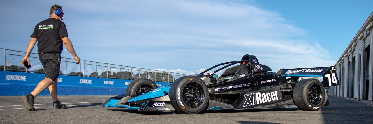 Blue X1 with crew member in pit lane
